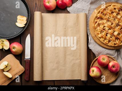 Rund gebackener Kuchen mit Apfelfüllung auf einem Holzbrett und Zutaten, brauner Tisch. Stockfoto