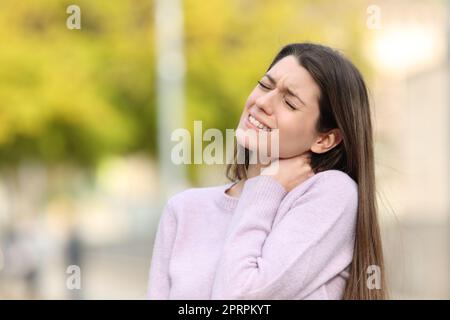 Ein Teenager, der sich im Park über Nackenschmerzen beschwert Stockfoto