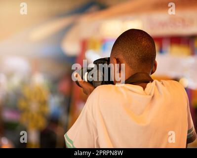 Die Sehenswürdigkeiten einfangen. Rückansicht eines jungen Mannes, der während einer Tour durch eine fremde Stadt Fotos gemacht hat. Stockfoto