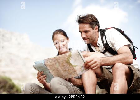 Hmm, die Route sieht gut aus...zwei Wanderer, die ihre Karte konsultieren, während sie auf einem Berggipfel sitzen. Stockfoto