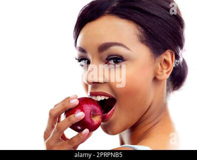 In ihren Lieblingssnack beißen. Studioportrait einer jungen Frau, die in einen Apfel beißt. Stockfoto