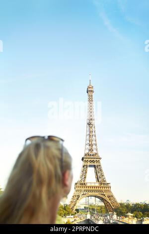 Erleben Sie die Schönheit der Eiffelturm. Rückansicht einer jungen Frau, die im Pariser Stadtbild sah. Stockfoto