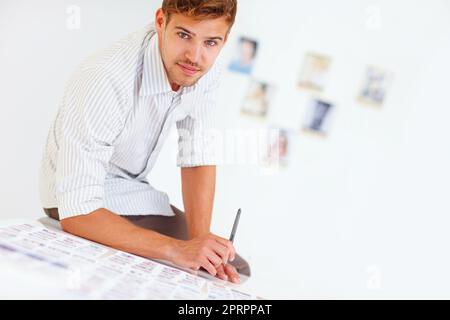 Hübscher Fotograf, der auf dem Tisch sitzt. Porträt eines hübschen Fotografen, der auf dem Tisch sitzt, mit Fotos. Stockfoto