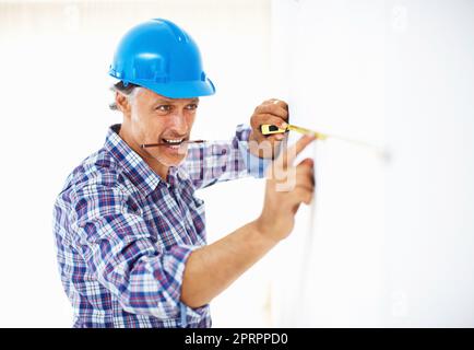 Reifer Ingenieur, der Wandmessungen annahm. Reifer Ingenieur in Harthut, der Messungen an der Wand abnimmt. Stockfoto