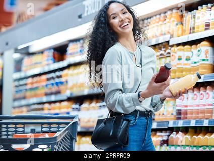 Frau mit Wahlmöglichkeit Lebensmittel einkaufen Saft im Geschäft, Kundin mit gesunder Ernährung im Supermarkt und zufrieden mit Einzelhandelsverkauf auf Lebensmittel im Markt. Porträt eines Mädchens mit Lächeln im Laden für Gesundheitsgetränke Stockfoto