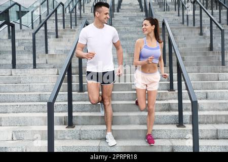 Mann und Frau in Fitnesskleidung laufen unten im Freien Stockfoto