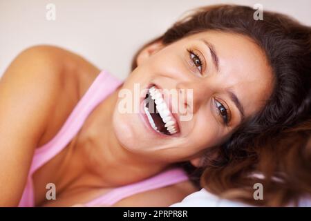 Frau mit einem breiten Lächeln. Nahaufnahme einer hübschen Frau, die ein breites Lächeln auf den Lippen zaubert. Stockfoto