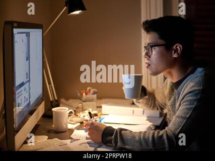 Etwas Koffein, um seine nächtliche Cram-Session zu unterstützen. Ein junger Student studiert bis spät in die Nacht. Stockfoto