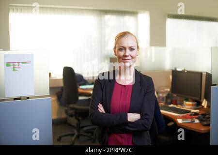Ich Spiele hart, wenn die Arbeiten erledigt sind. Porträt einer attraktiven Geschäftsfrau, die mit gekreuzten Armen im Büro steht. Stockfoto