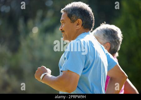 Aktiv bleiben. Ein reifes Paar joggt gemeinsam an einem sonnigen Tag. Stockfoto