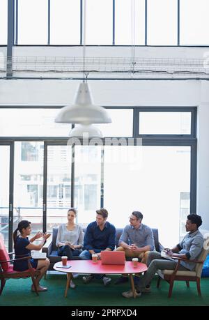 Es geht um neue Strategien. Eine Gruppe von Büromitarbeitern, die sich in einem Besprechungsraum unterhalten. Stockfoto