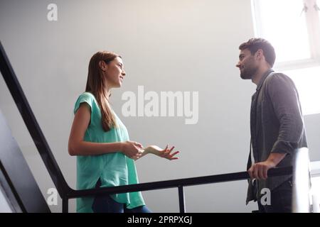 Ich bin froh, dass wir einen Moment zum Plaudern haben. Zwei Leute unterhalten sich im Treppenhaus. Stockfoto