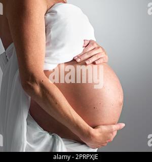 Sie erwartet ihre baldige Ankunft. Eine Schwangere hält ihren Bauch. Stockfoto