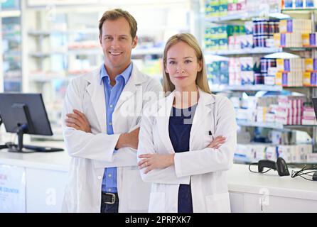 Zusammenarbeit mit Ärzten, um Ihre Gesundheit zu gewährleisten. Porträt von zwei Apothekern, die an der Rezeptheke stehen. Stockfoto