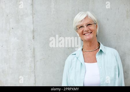 Sei du selbst, alle anderen werden getroffen. Porträt einer lächelnden älteren Frau. Stockfoto