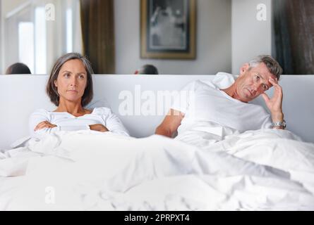 Sie sprechen nicht miteinander ... ein reifes Ehepaar verärgert miteinander im Schlafzimmer. Stockfoto