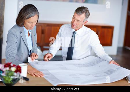 Bewertung der Pläne. Zwei reife Architekten diskutieren in einem Büro über Baupläne. Stockfoto