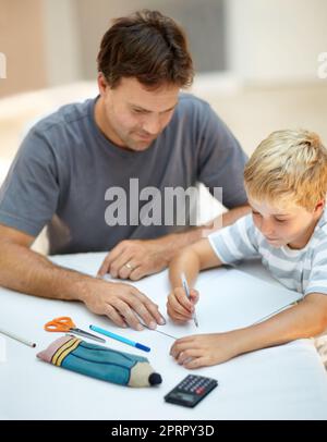 Vater ist immer bereit zu helfen - alleinender Vater. Der junge Vater hilft seinem Sohn bei seinen Schulaufgaben. Stockfoto