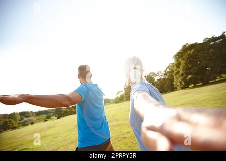 Nach Wellness greifen. Rückansicht eines reifen Paares, das im Freien Yoga macht. Stockfoto