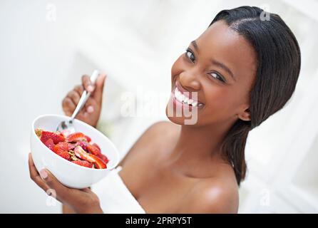 Ich beginne meinen Morgen auf die Erdbeerart. Eine schöne junge Frau, die eine Schüssel mit Erdbeerriem aß. Stockfoto