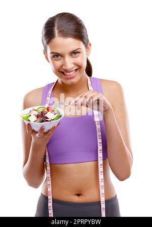 Fitness ist eine Belohnung, keine Strafe. Studio-Porträt einer schönen jungen Frau in Sportkleidung mit einer Schüssel Salat. Stockfoto