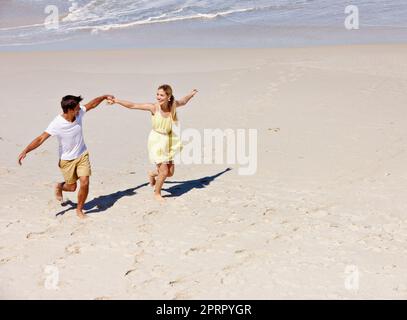 Am glücklichsten im Urlaub. Ein glückliches junges Paar genießt einen romantischen Spaziergang am Strand. Stockfoto