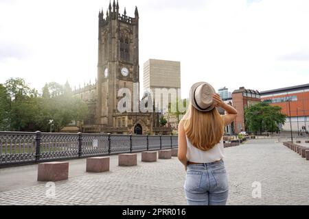 Rückansicht des schönen blonden Mädchens mit Hut zu Fuß in Manchester Stadt an sonnigen Tag, England, Vereinigtes Königreich Stockfoto