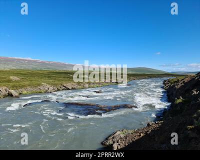 Fantastische Landschaft mit fließenden Flüssen und Bächen mit Felsen und Gras in Island. Stockfoto