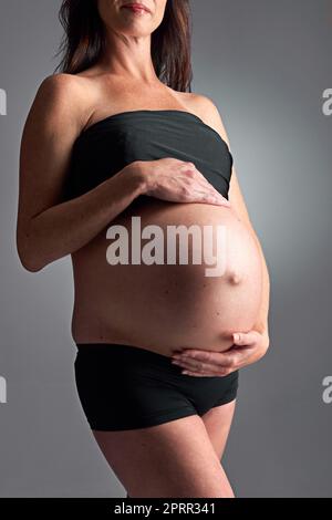 Sie erwartet ihre baldige Ankunft. Eine Schwangere hält ihren Bauch. Stockfoto