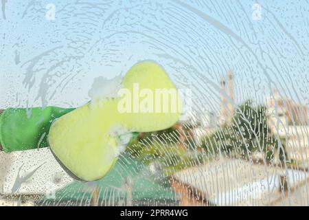 Person, die Glas mit Schwamm reinigt, Sicht von innen Stockfoto