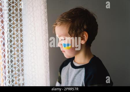 Porträt eines ukrainischen Jungen mit einem Gesicht in den Farben der ukrainischen Flagge. Stockfoto