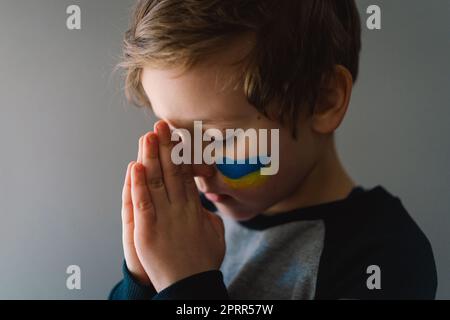 Der ukrainische Junge schloss die Augen und betete, den Krieg in der Ukraine zu beenden. Stockfoto