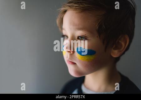 Porträt eines ukrainischen Jungen mit einem Gesicht in den Farben der ukrainischen Flagge. Stockfoto