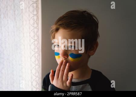 Porträt eines ukrainischen Jungen mit einem Gesicht in den Farben der ukrainischen Flagge. Stockfoto