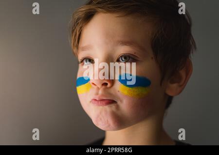 Porträt eines ukrainischen Jungen mit einem Gesicht in den Farben der ukrainischen Flagge. Stockfoto