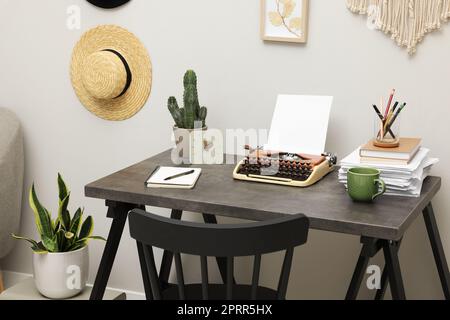 Schreibmaschine und Papierstapel auf dunklem Tisch im Zimmer. Schreibarbeitsplatz Stockfoto