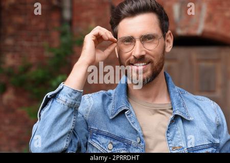 Lächelnder, gutaussehender Mann mit Brille draußen Stockfoto