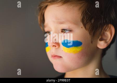 Porträt eines ukrainischen Jungen mit einem Gesicht in den Farben der ukrainischen Flagge. Stockfoto