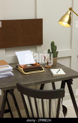 Schreibmaschine und Papierstapel auf dunklem Tisch im Zimmer. Schreibarbeitsplatz Stockfoto