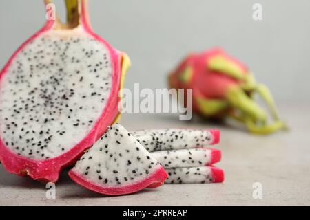 Köstliche geschnittene Drachenfrucht (Pitahaya) auf grauem Tisch, Nahaufnahme Stockfoto