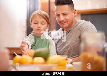 Ein kleines Mädchen, das mit ihrem Vater zu Hause frühstückt. Stockfoto