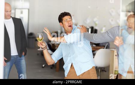 Die Büroparty ist schief gelaufen. Ein betrunkener Mann, der ein Glas Wein in der Hand hält, kämpft in einem Bürogesellschaftsbüro. Stockfoto