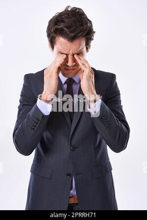 Durch Stress gekettet. Studioaufnahme eines hübschen jungen Geschäftsmannes in Handschellen. Stockfoto