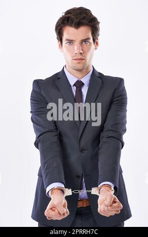 An sein Geschäft gebunden. Studioaufnahme eines hübschen jungen Geschäftsmannes in Handschellen. Stockfoto