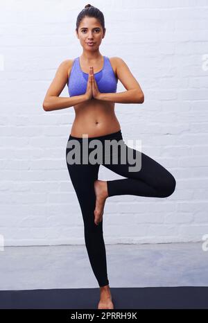 Halten Sie Ihr Gleichgewicht. Porträt einer attraktiven jungen Frau, die in einer Yoga-Pose steht. Stockfoto