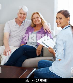 Termin muss nicht stressig sein. Ein glückliches Seniorenpaar mit einer jungen Krankenschwester, während sie ein digitales Tablet hält. Stockfoto