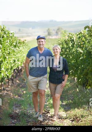 Spaziergang durch die Reben. Content reifes Paar verbringt Zeit in ihrem Weinberg. Stockfoto