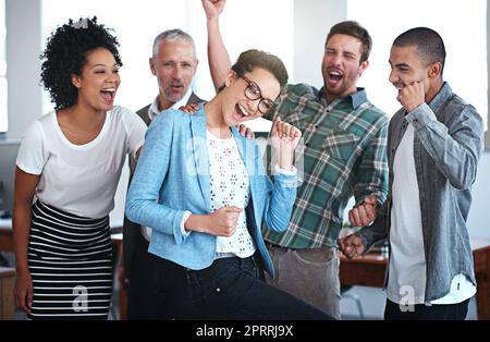 Wir feiern ihren Erfolg. Porträt einer Gruppe von Kollegen, die jubeln, während sie in einem Büro stehen. Stockfoto