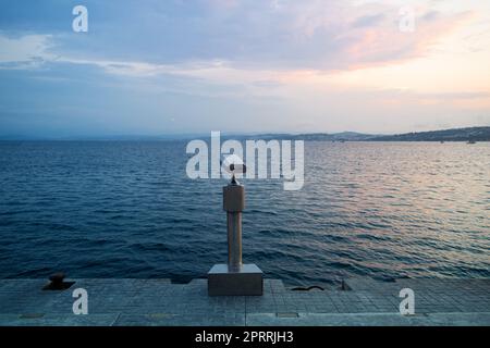 Münzbetätigte metallische Ferngläser auf Betonpier am Meer Stockfoto