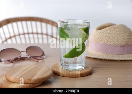 Ein Glas Limonade und stilvolle Tassen Untersetzer auf einem Holztisch Stockfoto